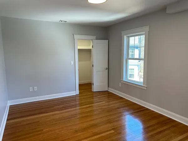 a view of an empty room with wooden floor and a window