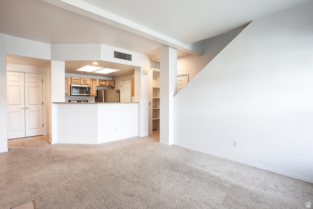 900 Bitner Road, Unit H35 Park City, UT 84098 - Photo 3 of 14 Open-concept living space featuring a curved white kitchen island with wood-finish cabinetry, stainless steel appliances, and ample counter workspace