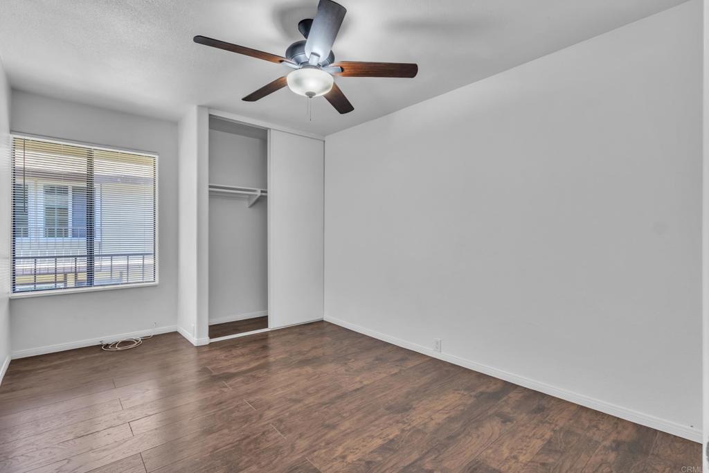237 Rancho Drive, Unit C Chula Vista, CA 91911 - Photo 11 of 23 an empty room with wooden floor chandelier fan and windows
