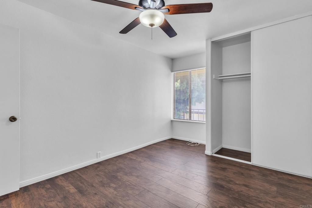 237 Rancho Drive, Unit C Chula Vista, CA 91911 - Photo 13 of 23 an empty room with wooden floor chandelier fan and windows