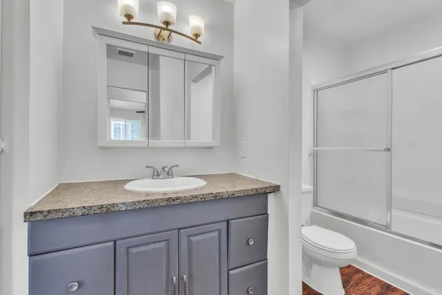 a bathroom with a granite countertop toilet sink and mirror