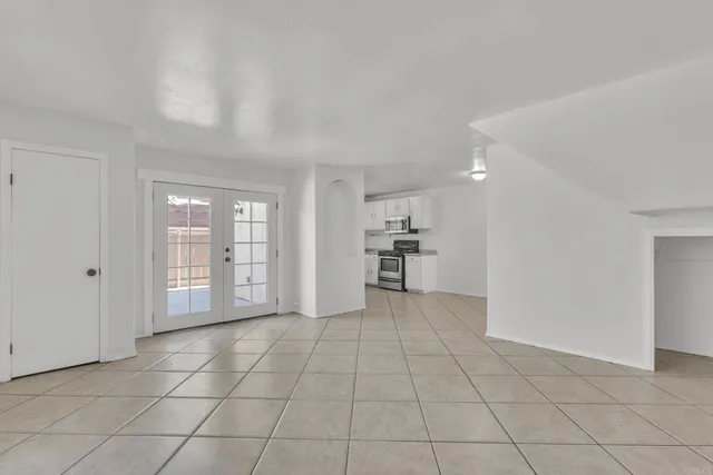 a view of an empty room with kitchen and window