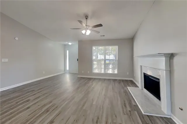 an empty room with wooden floor fireplace and windows