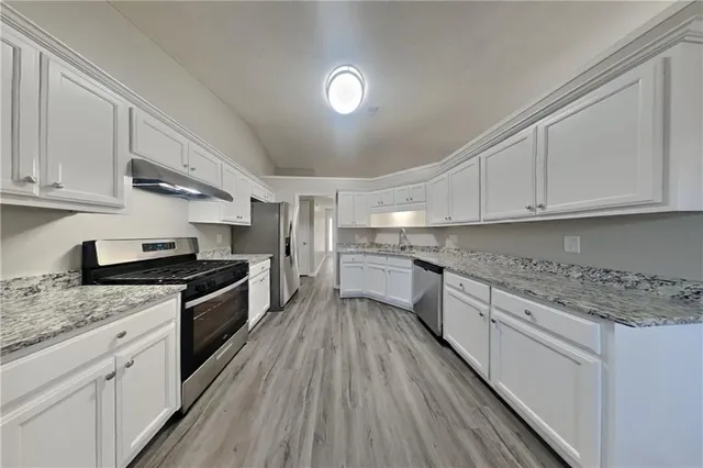 a kitchen with granite countertop a sink cabinets stainless steel appliances and a counter space