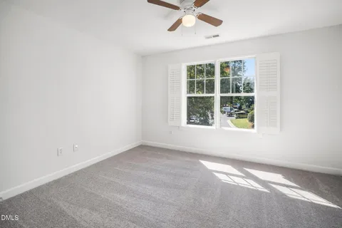 an empty room with a ceiling fan and a window
