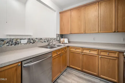 a kitchen with stainless steel appliances granite countertop a refrigerator a stove and a sink with wooden cabinets