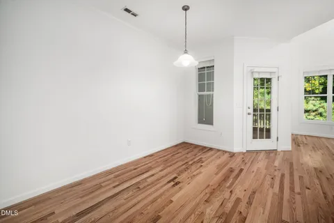 a view of an empty room with wooden floor fireplace and a window