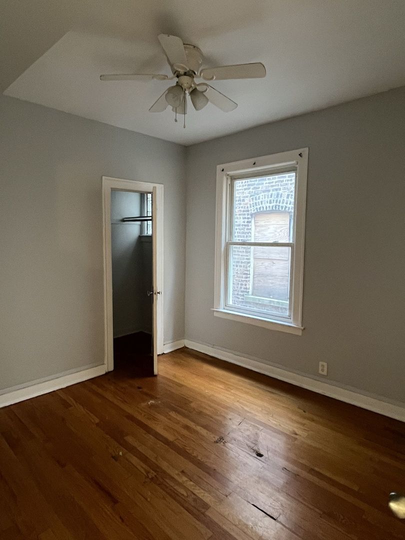 8019 South Vernon Avenue, Unit 2 Chicago, IL 60619 - Photo 7 of 13 a view of an empty room with wooden floor and a window