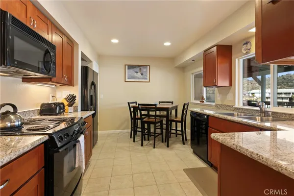 a kitchen with stainless steel appliances granite countertop a stove top oven a sink a dining table and chairs with wooden floor