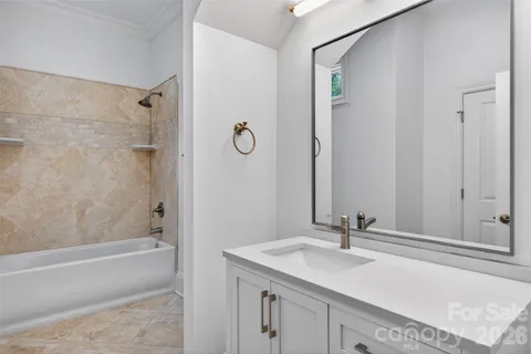a bathroom with a granite countertop sink a mirror and a bathtub