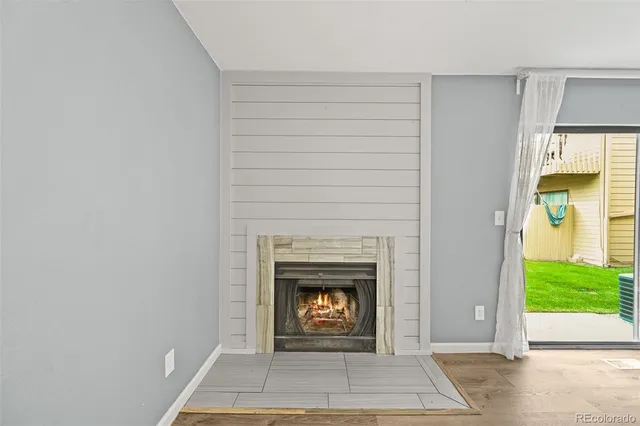 a view of an empty room with wooden floor and a fireplace