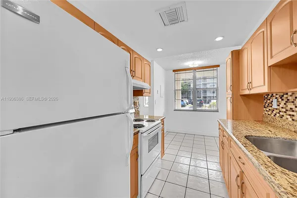 a kitchen with stainless steel appliances granite countertop a refrigerator a sink and white cabinets