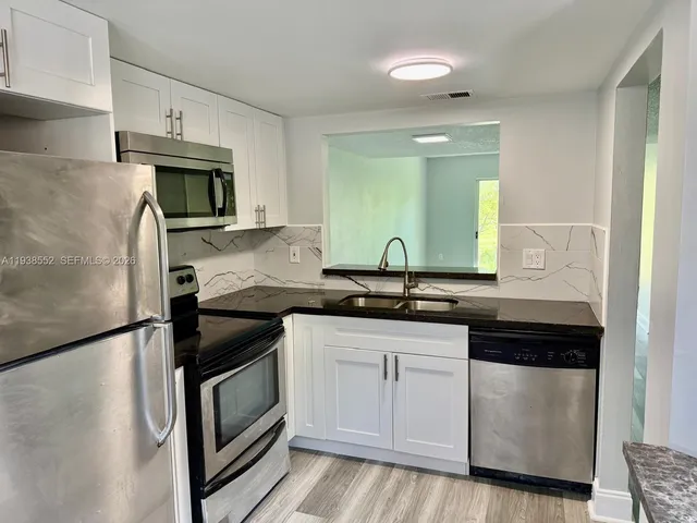 a kitchen with granite countertop white cabinets and stainless steel appliances