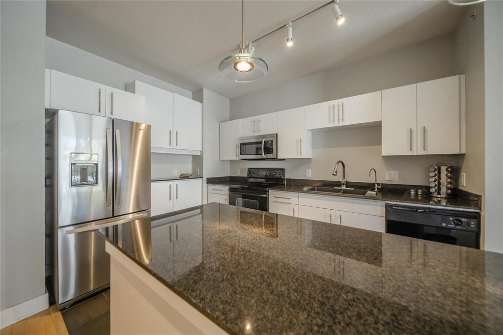 4414 Cedar Springs Road, Unit 214 Dallas, TX 75219 - Photo 8 of 29 Kitchen featuring black appliances, dark stone countertops, white cabinetry, and decorative light fixtures