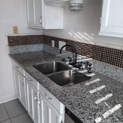 a kitchen with granite countertop white cabinets and black appliances