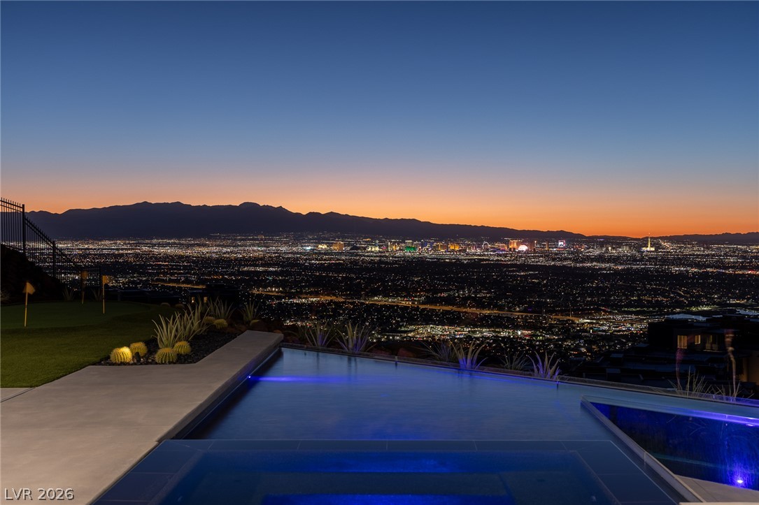 563 Grand Rim Drive Henderson, NV 89012 - Photo 52 of 70 An illuminated infinity pool perfectly frames the sweeping cityscape at twilight.
