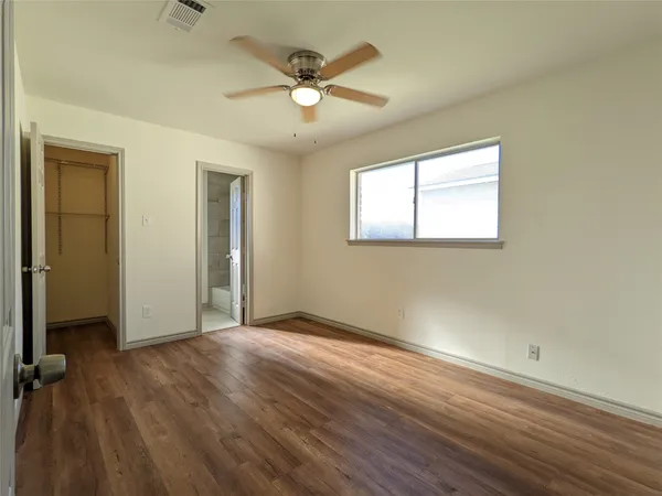 an empty room with wooden floor chandelier fan and windows