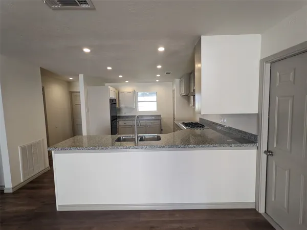 a large kitchen with stainless steel appliances granite countertop a large counter top and a refrigerator