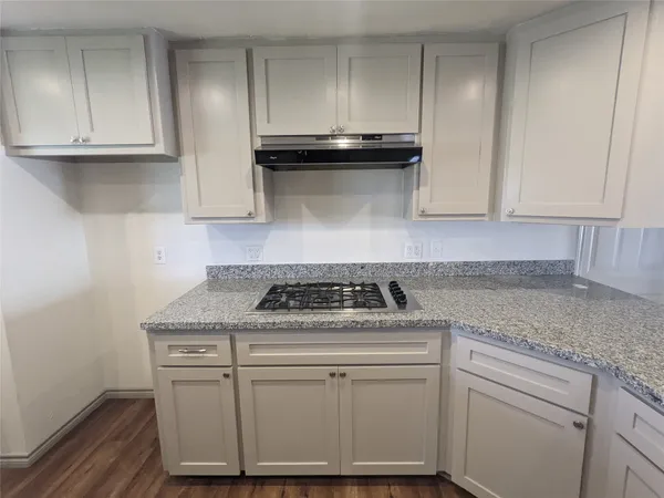 a kitchen with granite countertop white cabinets and a stove