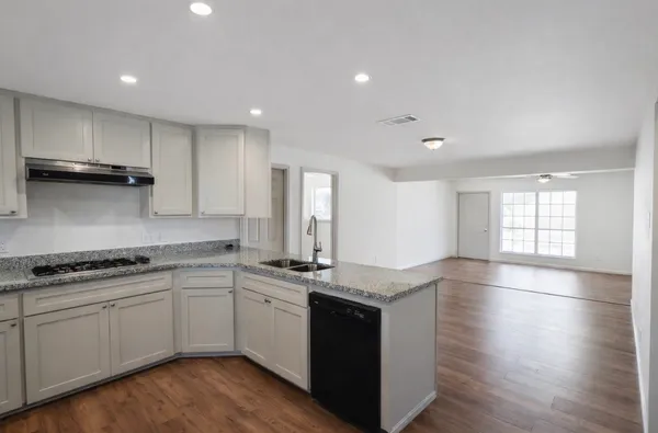 a kitchen with stainless steel appliances granite countertop a stove a sink and white cabinets