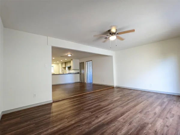 a view of an empty room with window and wooden floor