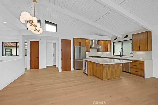 a large kitchen with stainless steel appliances granite countertop a stove a sink dishwasher and a refrigerator with wooden floor