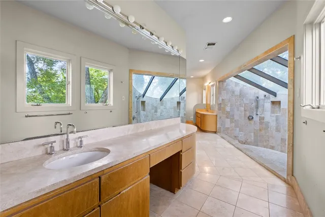 a spacious bathroom with a granite countertop sink a toilet a mirror and next to a window