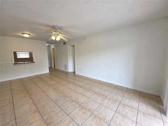 a view of an empty room and chandelier fan