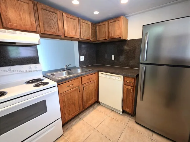 a kitchen with stainless steel appliances granite countertop a refrigerator a stove a sink and a microwave