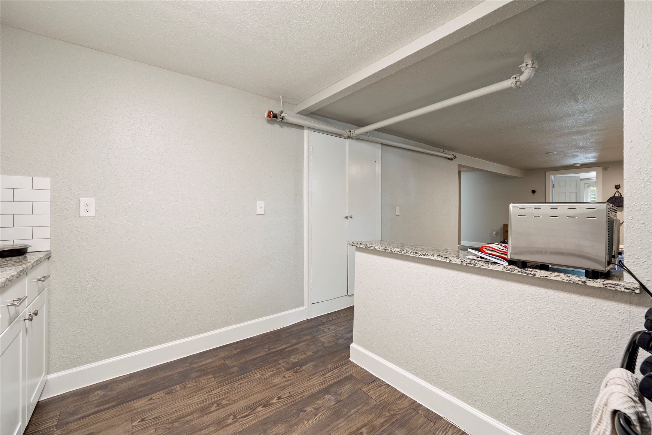 201 West 31st Street, Unit E Austin, TX 78705 - Photo 10 of 16 A compact kitchen area features modern cabinetry, granite counters, and rich hardwood flooring.