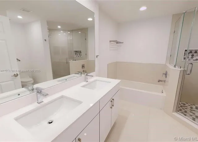 a bathroom with a double vanity sink mirror and bathtub