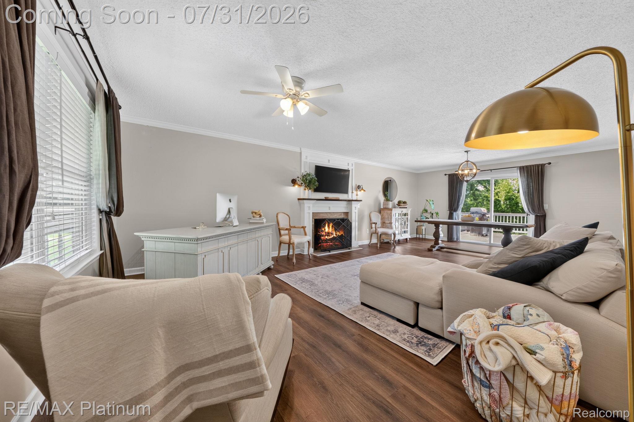 2401 Golf Club Road Howell, MI 48843 - Photo 5 of 37 Great room with gas fireplace, LVP flooring, crown molding, and a ceiling fan.