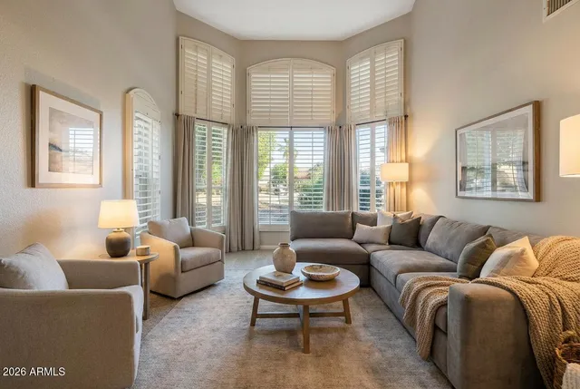 a spacious bedroom with a bed a chandelier and windows