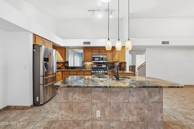 a kitchen with stainless steel appliances granite countertop a sink a stove and a refrigerator
