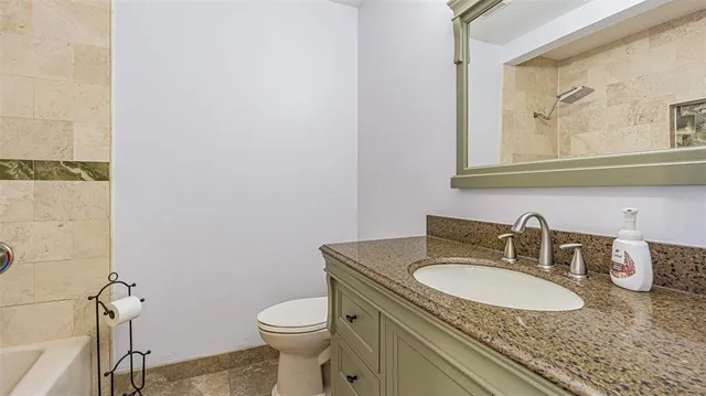 a bathroom with a granite countertop sink a toilet and a mirror