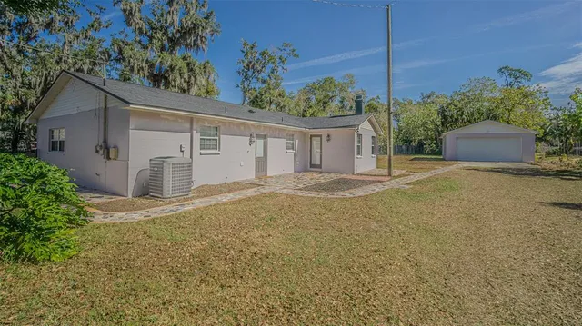 a view of a white house next to a yard and palm trees