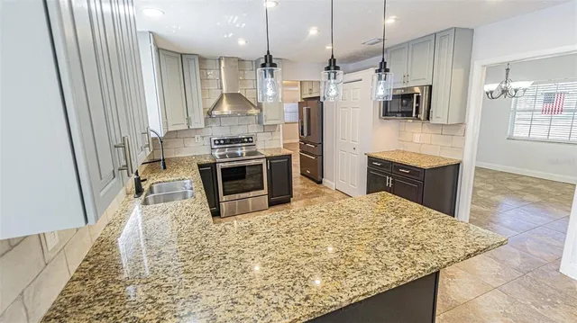 a kitchen with stainless steel appliances granite countertop a stove top oven a sink and a refrigerator