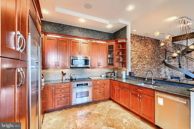 a large kitchen with stainless steel appliances granite countertop a sink and cabinets