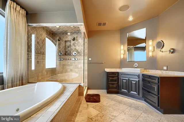 a bathroom with a tub a sink and mirror