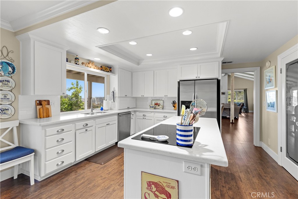 3237 Canonita Drive Fallbrook, CA 92028 - Photo 11 of 55 a kitchen with stainless steel appliances kitchen island granite countertop a refrigerator a sink dishwasher and white cabinets with wooden floor