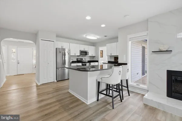 a kitchen with stainless steel appliances granite countertop a refrigerator a stove top oven a sink and white cabinets with wooden floor