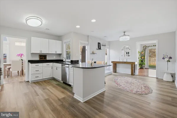 a kitchen with granite countertop a stove a sink dishwasher and a refrigerator with white cabinets
