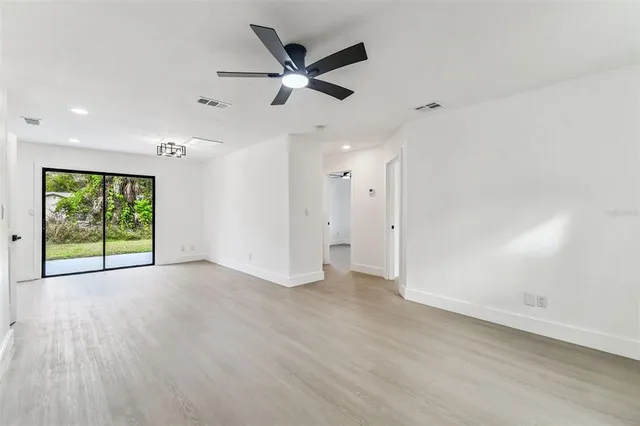 an empty room with wooden floor fan and windows