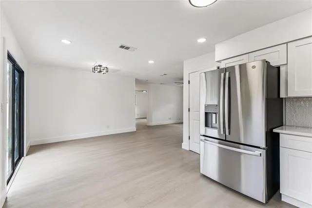 a view of kitchen with refrigerator and white cabinets