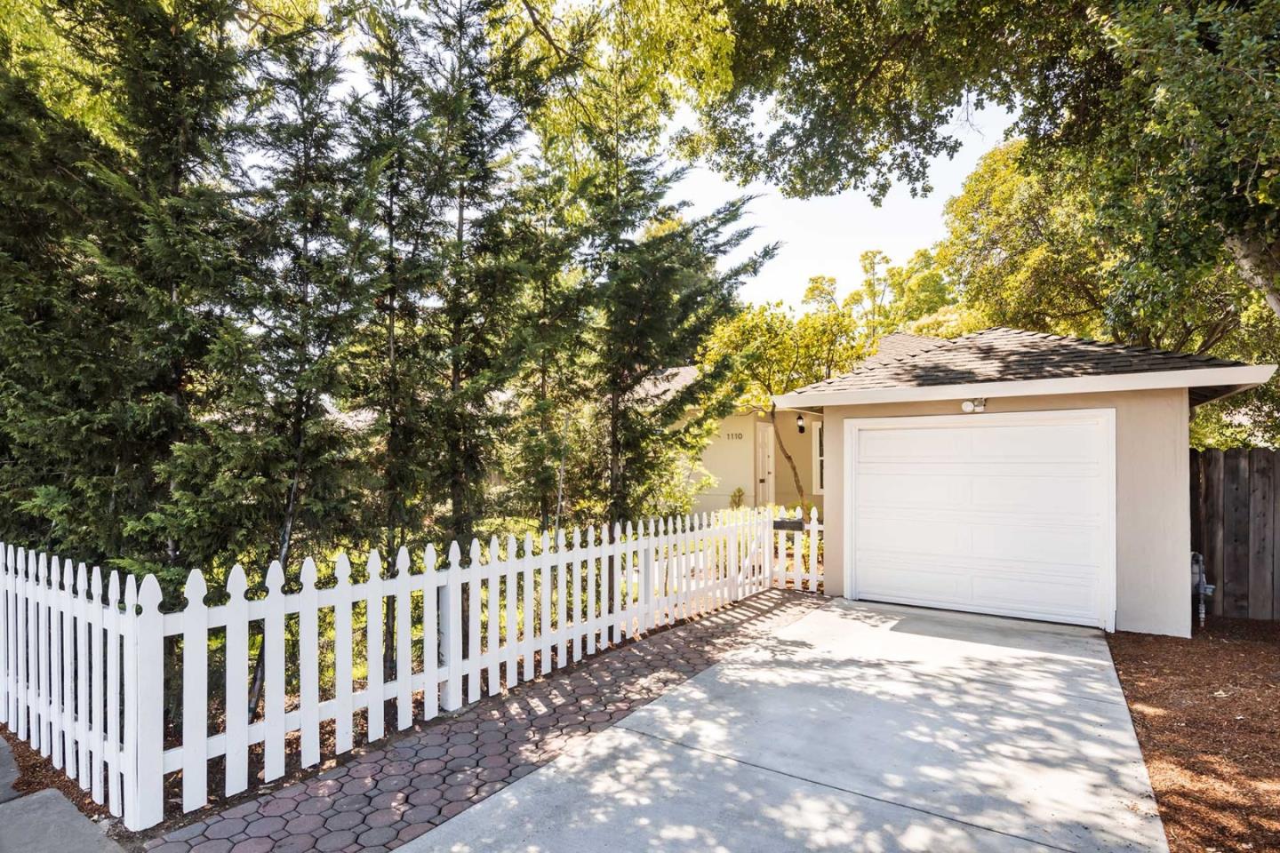 1110 Embarcadero Road Palo Alto, CA 94303 - Photo 3 of 23 a view of a white house with a large tree and wooden fence