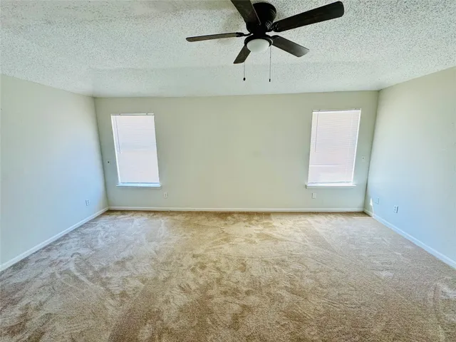 an empty room with a window and a fan