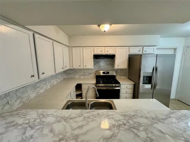 a kitchen with granite countertop a refrigerator and a stove