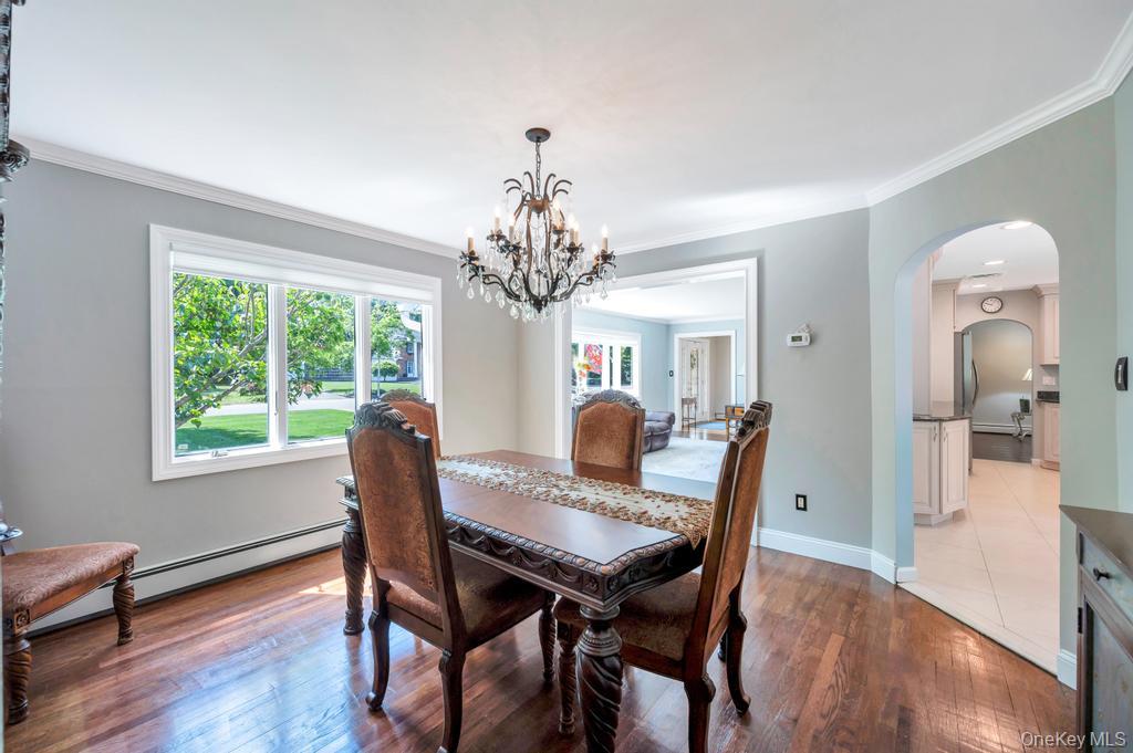 10 South Lot Road Smithtown, NY 11787 - Photo 8 of 50 Formal dining space featuring wood-finish flooring, a contemporary chandelier, crown molding, and a wide window with white trim