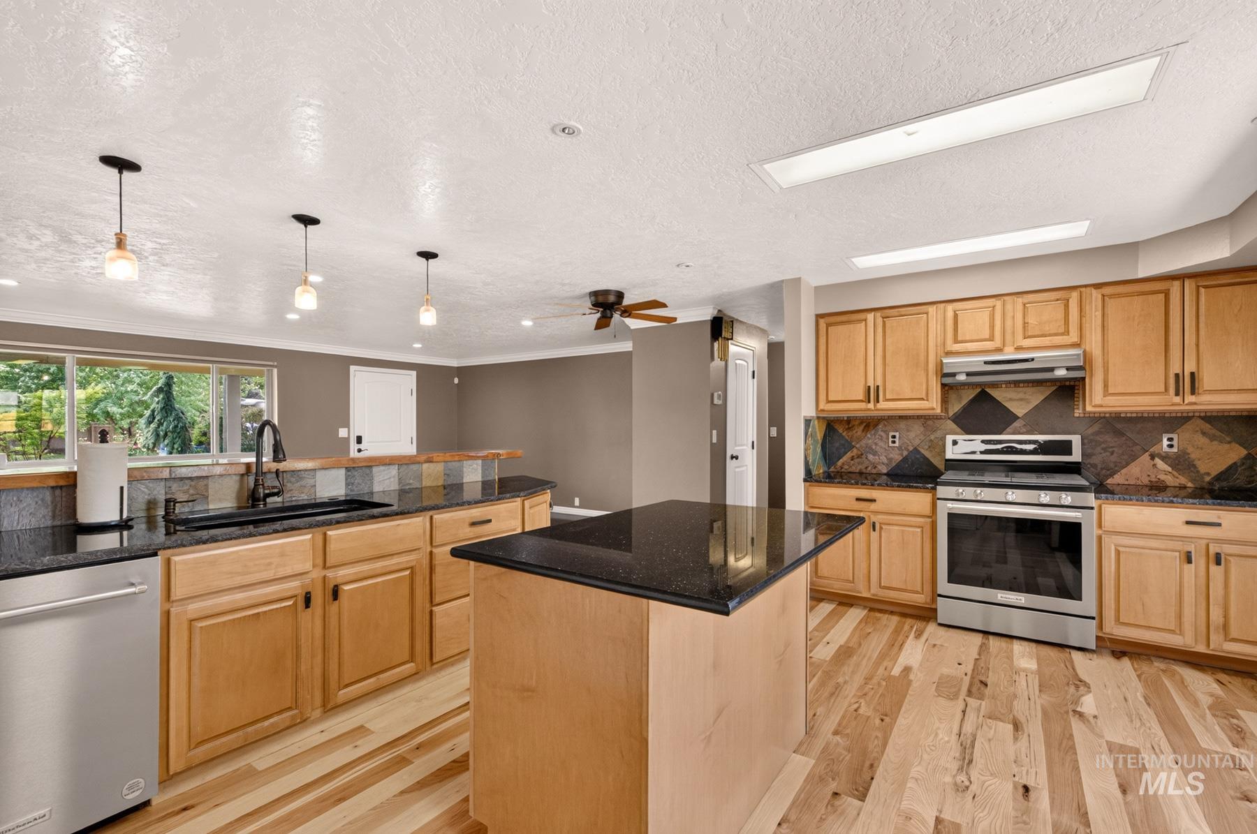 9622 Delaware Street Boise, ID 83709 - Photo 18 of 48 Spacious kitchen featuring wood-finish flooring, light wood cabinetry, and a central island with a dark countertop