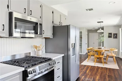 a kitchen with stainless steel appliances granite countertop a stove a refrigerator and a dining table with wooden floor